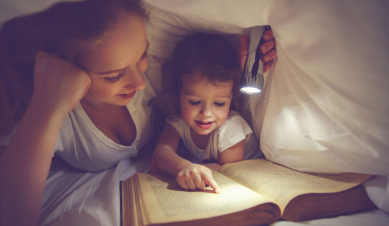 Family reading bedtime. Mom and child daughter reading a book with a flashlight under the blanket in bed
** Note: Soft Focus at 100%, best at smaller sizes